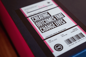 Close-up photo of the Purpose sticker on a Map Room brand box reading: Creating Outcomes That Change Lives.
